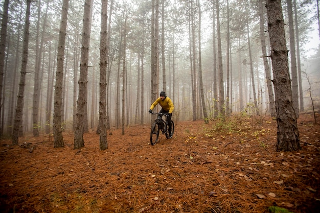 Handsome young man biking through autumn forest