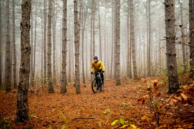 Handsome young man biking through autumn forest