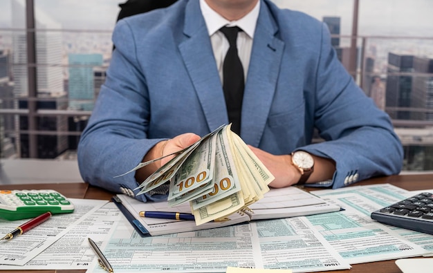 Handsome young man in black clothes making calculations over his own business at the table Business and forms concept