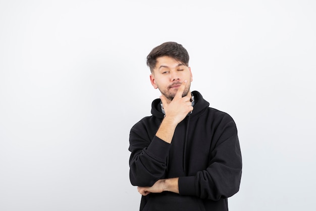 Handsome young man in black hoodie wearing big wireless music headphones 