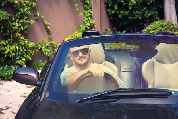 Handsome young man in a cabriolet enjoys life