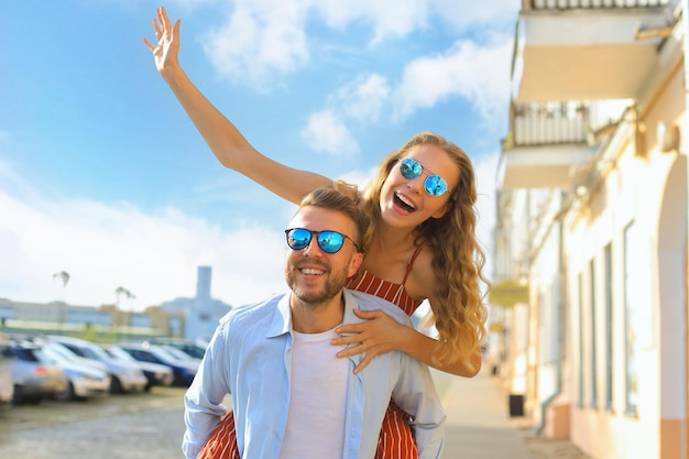 Handsome young man carrying young attractive woman on shoulders while spending time together outdoors