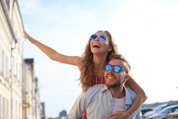 Handsome young man carrying young attractive woman on shoulders while spending time together outdoors.