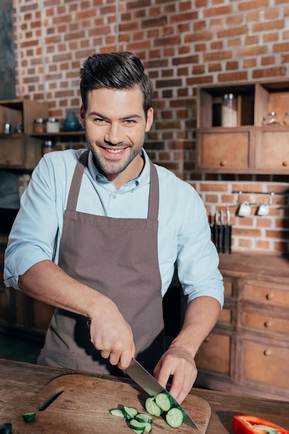 Handsome young man cutting vegetables