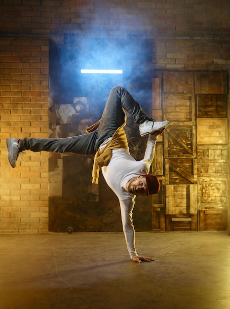 Handsome young man developing freeze over dance studio background