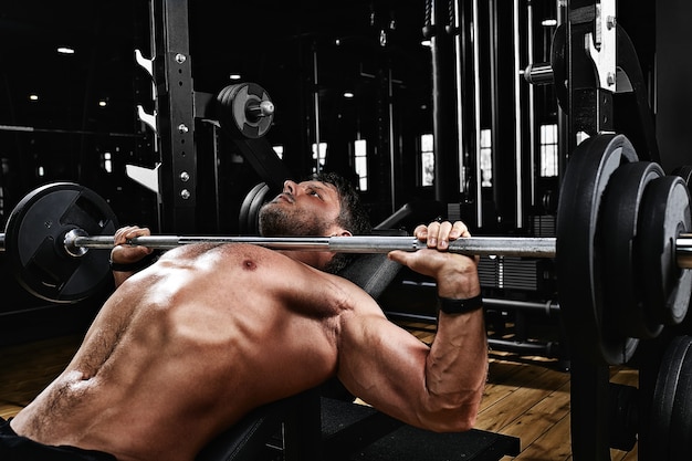 Handsome young man doing bench press workout in gym,