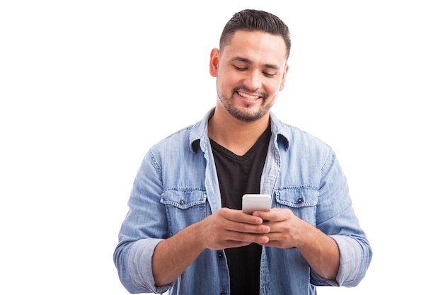 Handsome young man dressed casually and using a smartphone on a white background