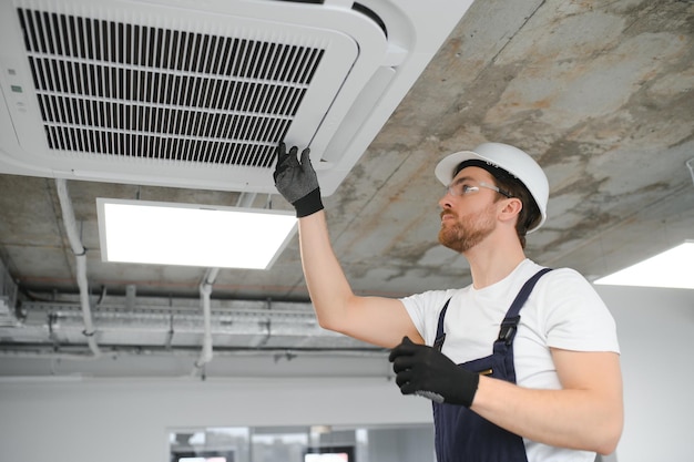 Handsome young man electrician installing air conditioning