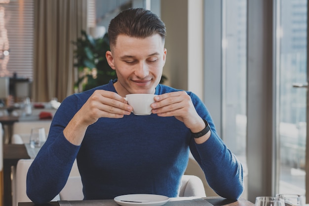 Handsome young man having breakfast at the cafe