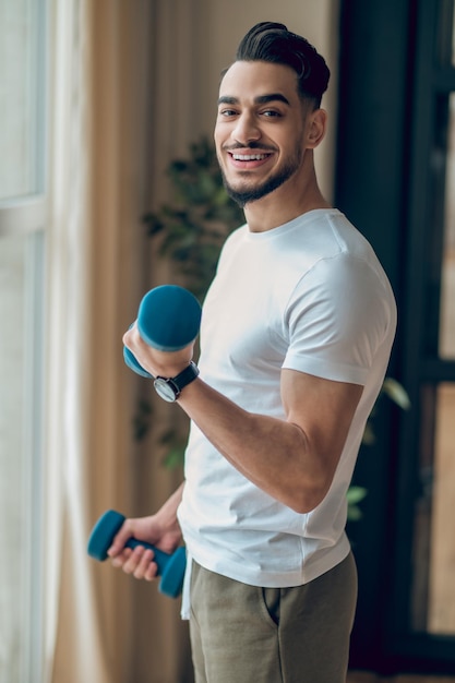 Handsome young man having a workout with dumbbells