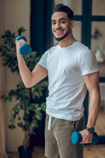 Handsome young man having a workout with dumbbells