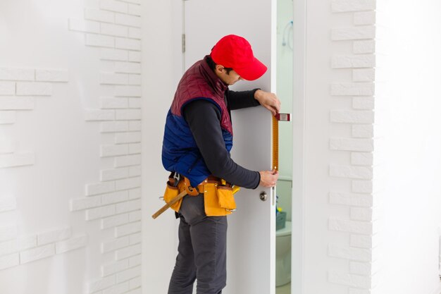 handsome young man installing a door in a new house construction site