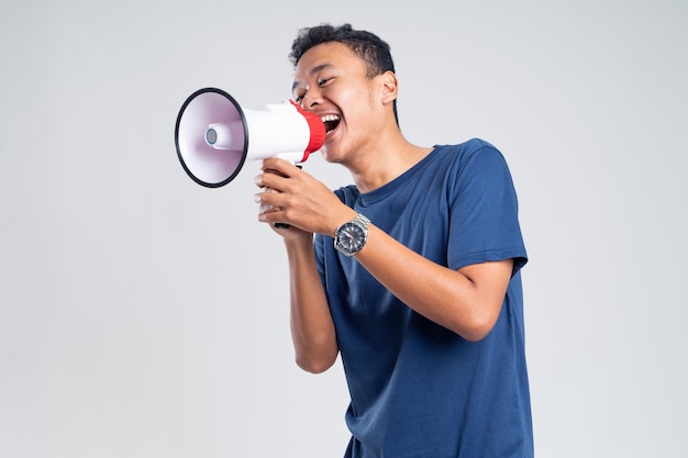 Handsome young man over isolated white background shouting through a megaphone