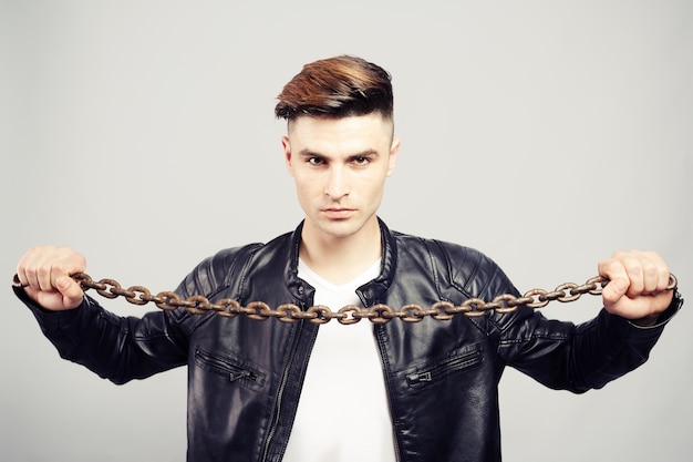 Handsome young man in leather jacket with metal chain