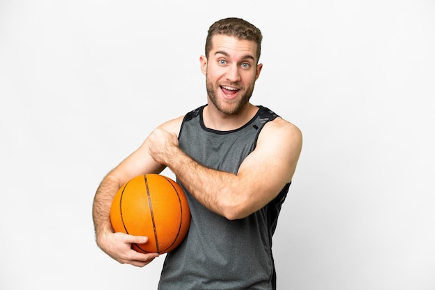 Handsome young man playing basketball over isolated white background celebrating a victory