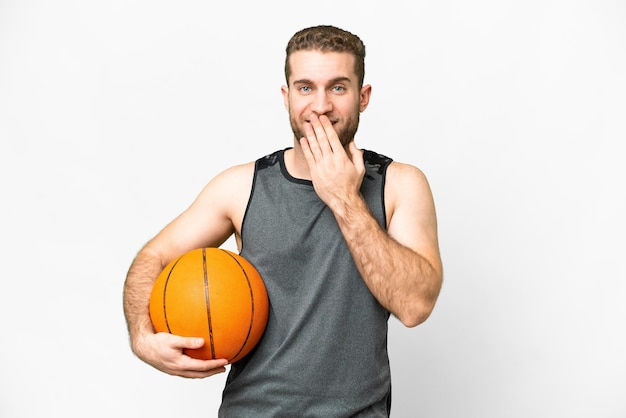 Handsome young man playing basketball over isolated white background happy and smiling covering mouth with hand