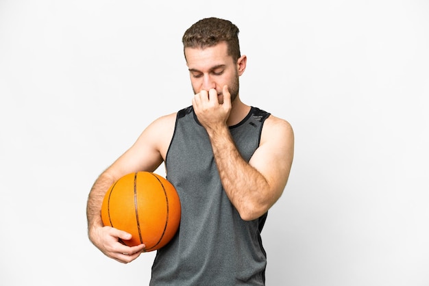 Handsome young man playing basketball over isolated white background having doubts