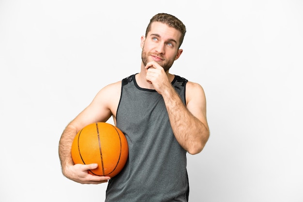 Handsome young man playing basketball over isolated white background and looking up