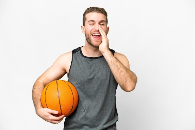 Handsome young man playing basketball over isolated white background shouting with mouth wide open