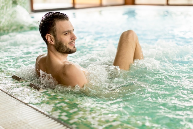 Handsome young man relaxing in hot tub