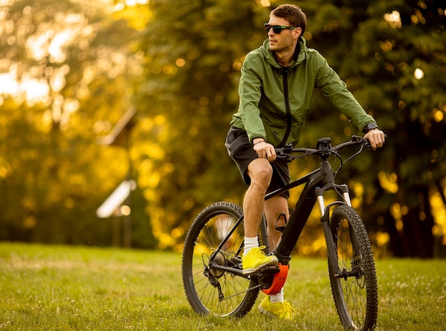 Handsome young man riding ebike in the park