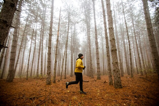 Handsome young man running in autumn forest and exercising for trail run marathon endurance race