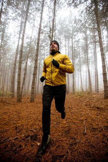 Photo handsome young man running in autumn forest and exercising for trail run marathon endurance race