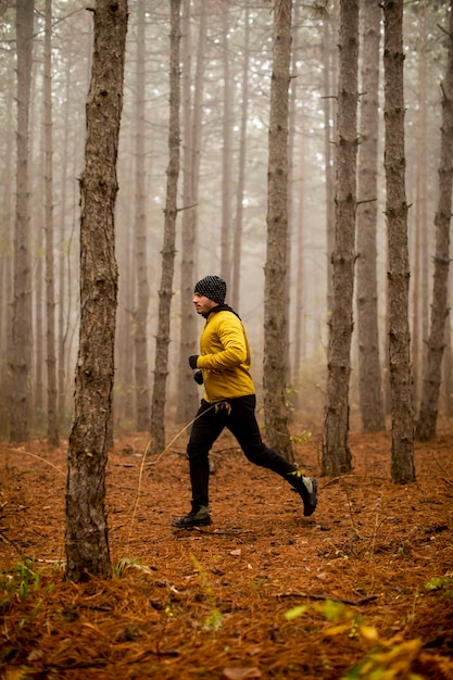 Handsome young man running in autumn forest and exercising for trail run marathon endurance race