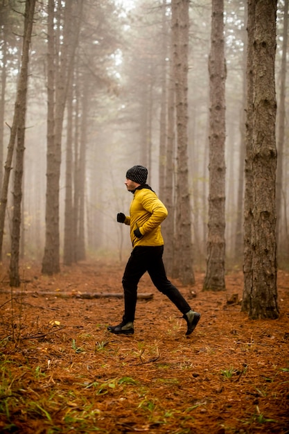 Handsome young man running in autumn forest and exercising for trail run marathon endurance race