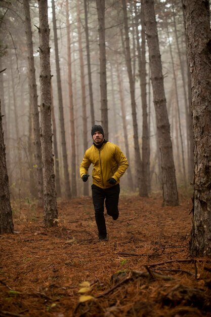 Handsome young man running in autumn forest and exercising for trail run marathon endurance race