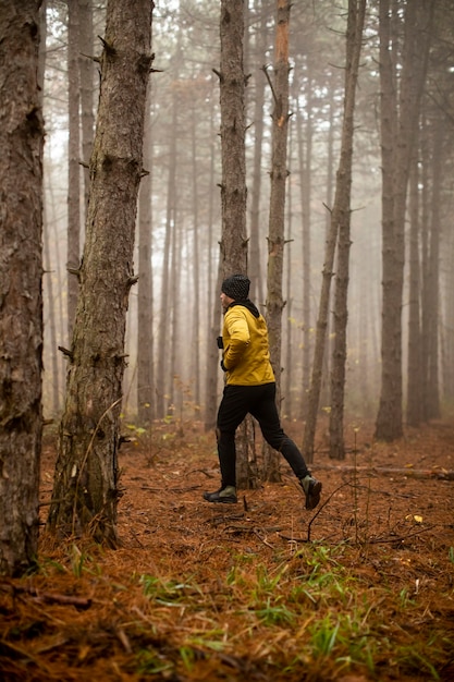 Handsome young man running in autumn forest and exercising for trail run marathon endurance race