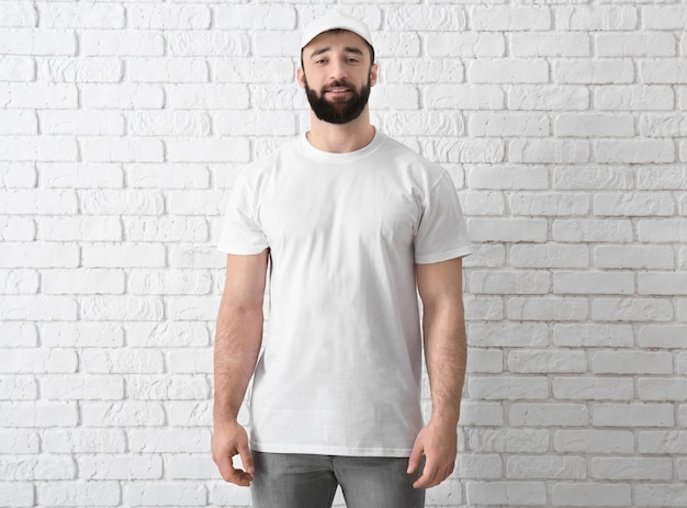 Handsome young man in stylish white tshirt near brick wall Mockup for design