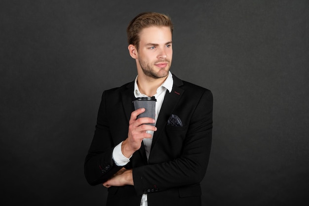 Handsome young man in suit with takeaway coffee