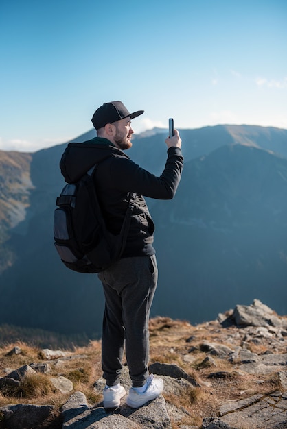 Handsome young man takeson smartphone mountain scenery.  Kasprowy Wierch. Poland.