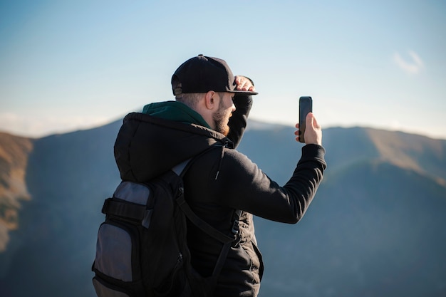 Handsome young man takeson smartphone mountain scenery.  Kasprowy Wierch. Poland.