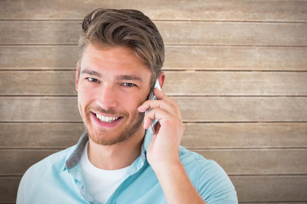 Handsome young man talking on his smartphone against wooden surface with planks