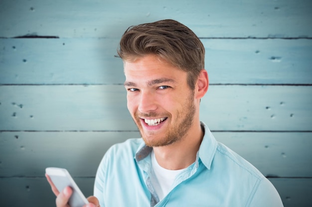 Handsome young man using his smartphone against painted blue wooden planks