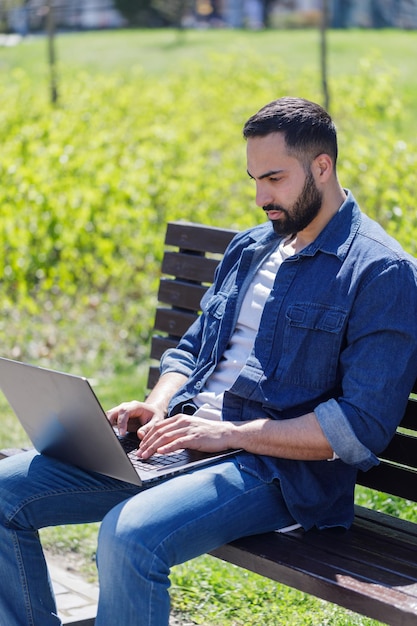 Handsome young man using laptop in city on a summer day