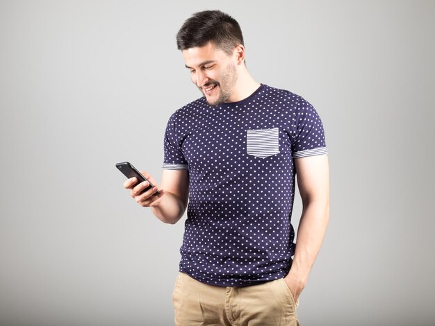 Handsome young man using smartphone isolated over gray background