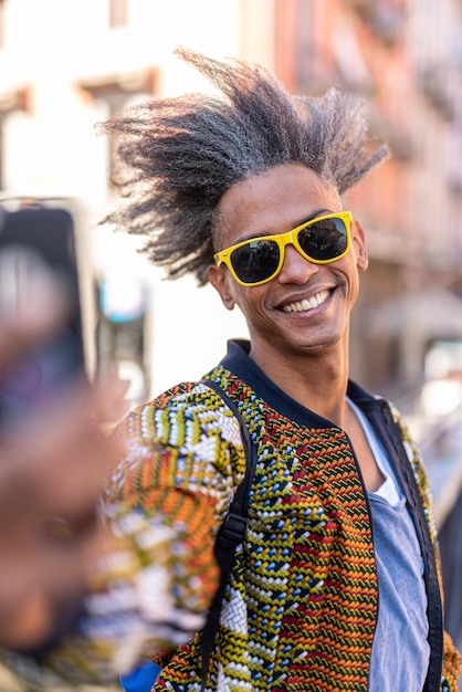 Handsome young man using smartphone for a selfie, casual and street wear, cool attitude, afro american mixed race people