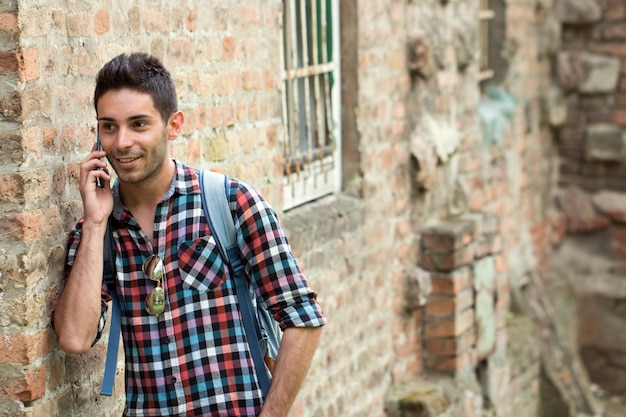 Handsome young man walking with mobile phone and backpack