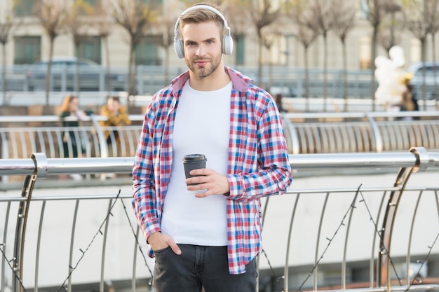 Handsome young man wear headphones casual dressed male drinking morning coffee from cup unshaven guy with bristle listen music urban style modern life concept student drink tea