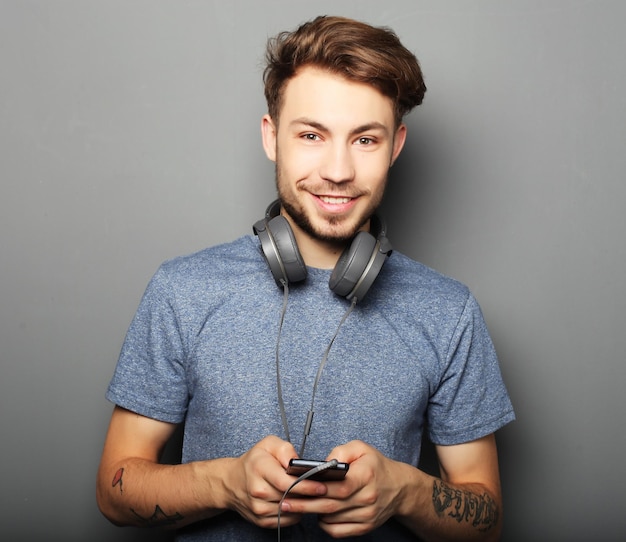 Handsome young man wearing headphones on his neck and smiling wh