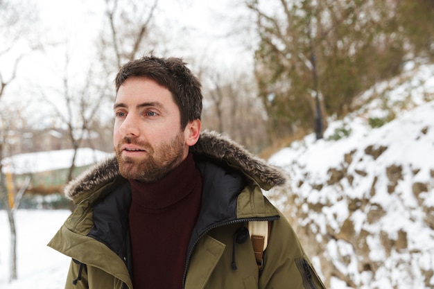 Handsome young man wearing winter jacket standing outdoors