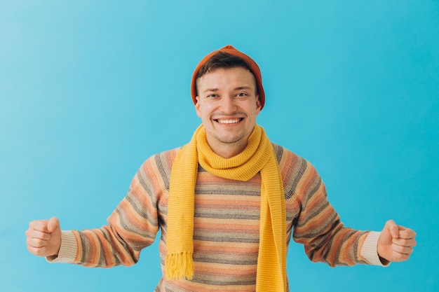 Handsome young man in winter clothes on color background The winner's gesturexA