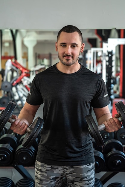 Handsome young man with a beautiful figure works as a fitness trainer in a prestigious gym