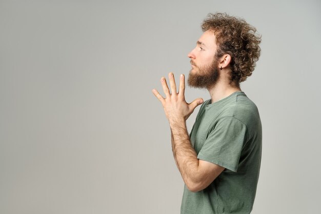 Handsome young man with curly hair in olive t-shirt looking at front isolated on white wall