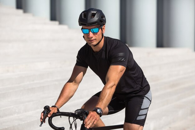 Handsome young man with helmet and sunglasses on a bike