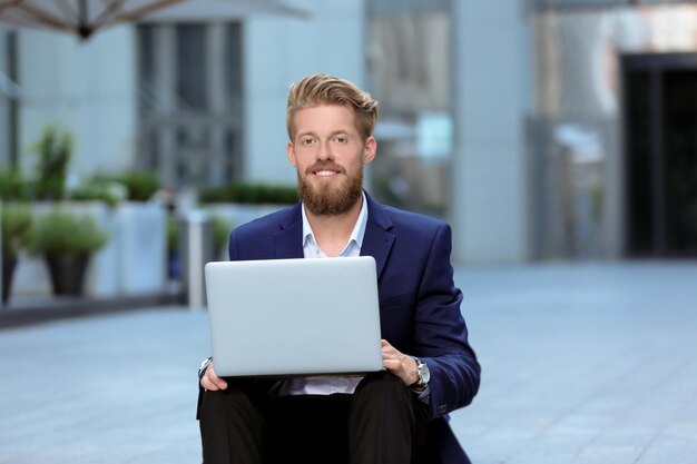 Photo handsome young man with laptop outdoors