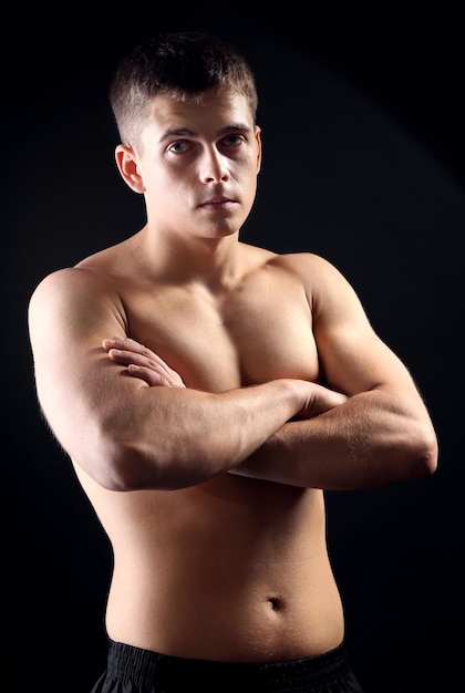 Handsome young muscular sportsman on dark background